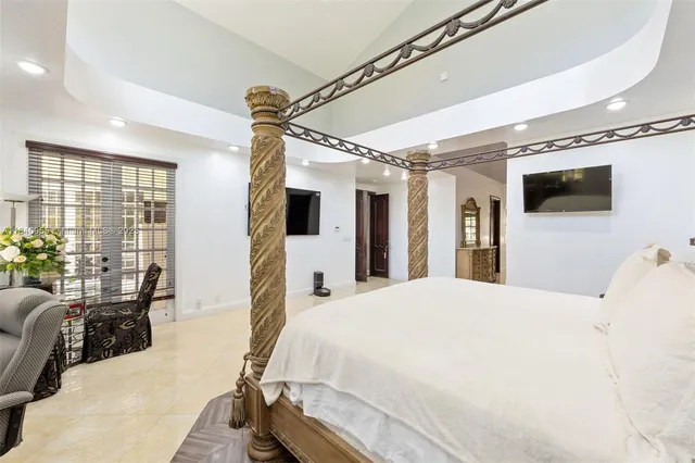 a spacious bedroom with a bed window and flat screen tv