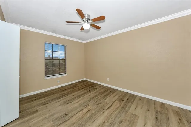 an empty room with wooden floor fan and windows