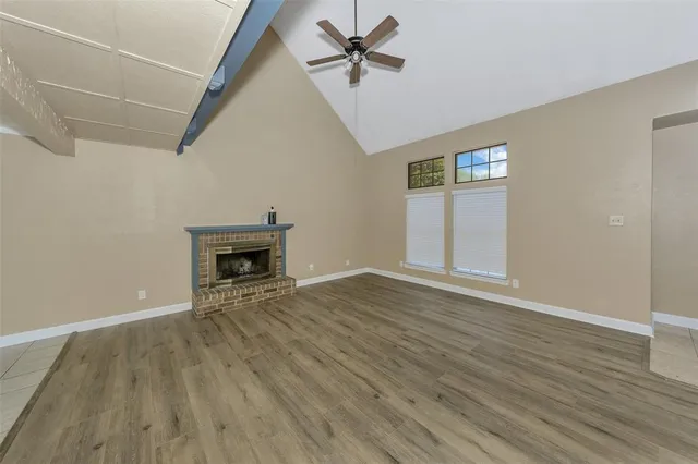 a view of an empty room with wooden floor and a fireplace