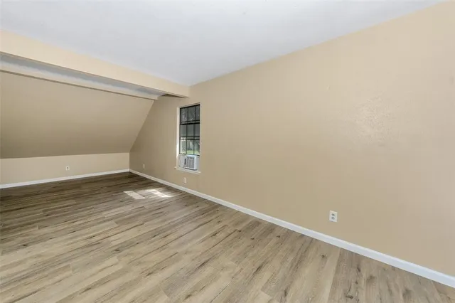 a view of an empty room with wooden floor and windows