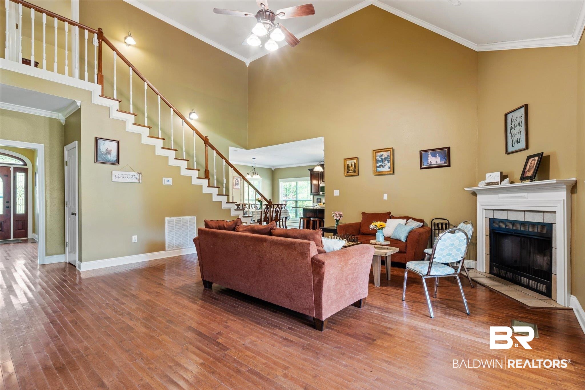 72 Limestone Drive Jackson, AL 36545 - Photo 10 of 38 Living room featuring a tile fireplace, wood-type flooring, ceiling fan, ornamental molding, and a towering ceiling
