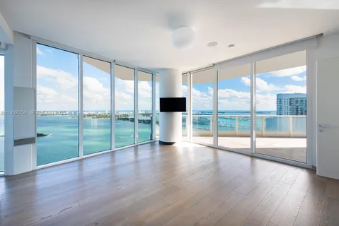 a view of empty room with wooden floor and floor to ceiling window