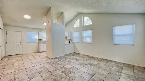 an empty room with kitchen view and a window