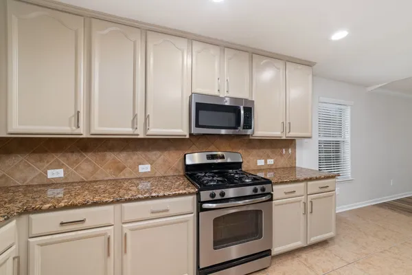 a kitchen with granite countertop white cabinets and stainless steel appliances