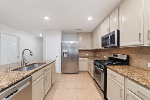 a kitchen with stainless steel appliances granite countertop a stove a sink dishwasher a refrigerator and a microwave