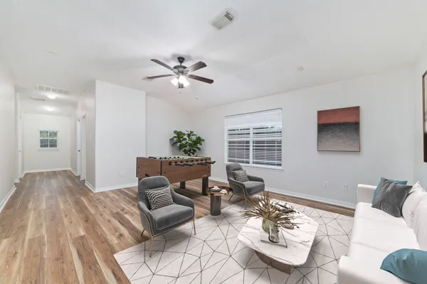 an empty room with wooden floor ceiling fan and windows
