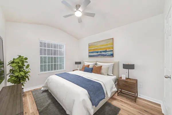an empty room with wooden floor fan and windows