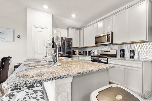 a kitchen with kitchen island granite countertop a sink a stove and cabinets