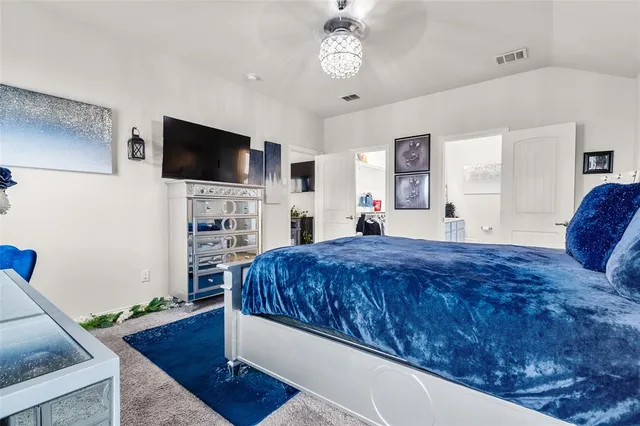 a spacious bedroom with a bed and a flat screen tv