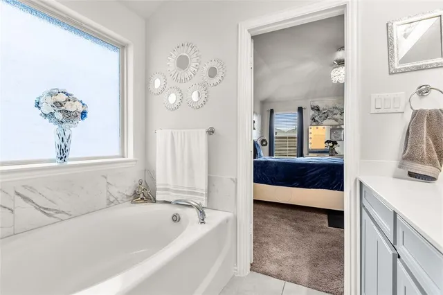 a en suite bathroom with a tub double vanity and chandelier