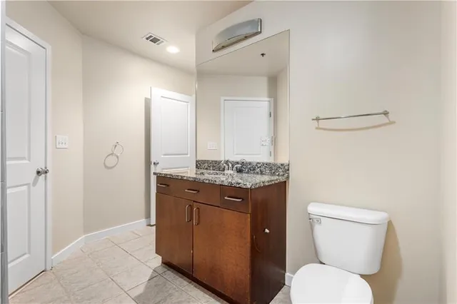 a bathroom with a granite countertop toilet sink and mirror