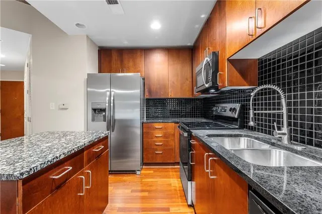 a kitchen with stainless steel appliances granite countertop a sink and a refrigerator