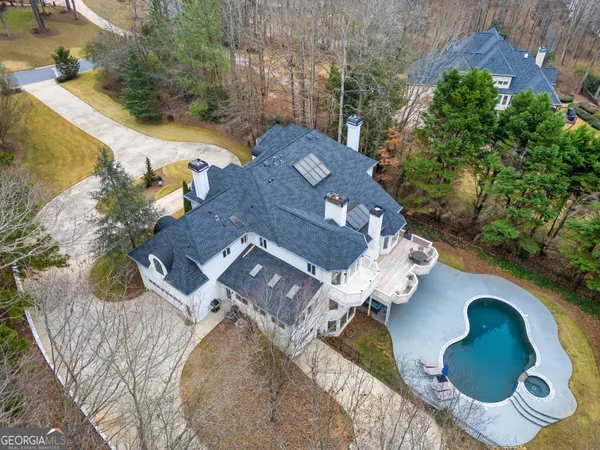 an aerial view of a house with swimming pool and large trees