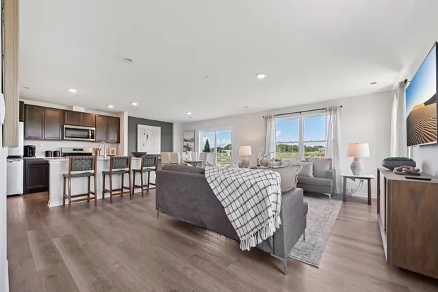 a living room with furniture kitchen view and a wooden floor