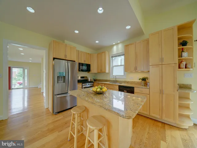 a large kitchen with a large counter top wooden cabinets and stainless steel appliances