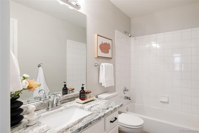 a bathroom with a granite countertop sink a toilet and shower