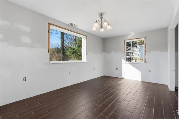 an empty room with wooden floor chandelier and windows