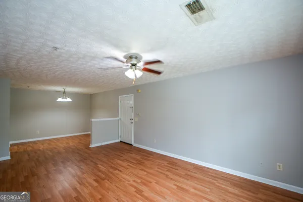 an empty room with wooden floor fan and windows