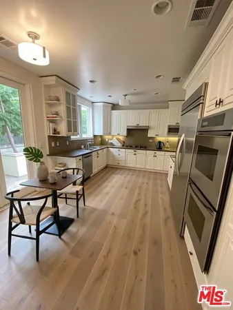 a living room with couches chairs and kitchen view with wooden floor