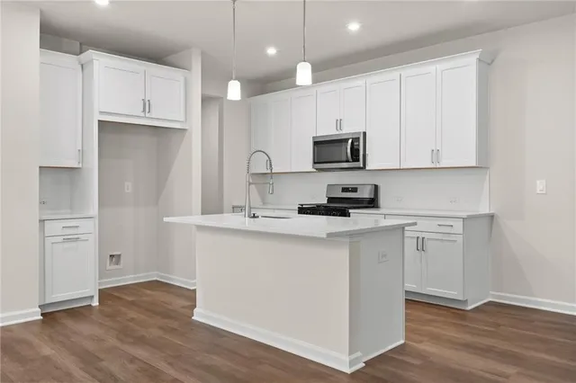 a kitchen with cabinets stainless steel appliances a sink and wooden floor