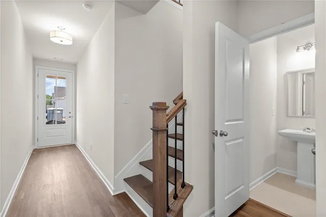 a view of a hallway with wooden floor and a bathroom