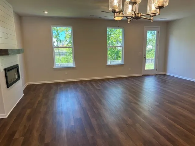 an empty room with wooden floor windows and chandelier