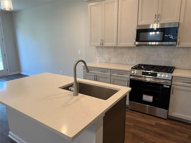 a kitchen with stainless steel appliances a stove a microwave a sink a refrigerator and cabinets