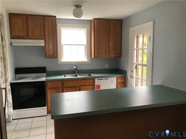 a open kitchen with granite countertop a stove a sink and a microwave