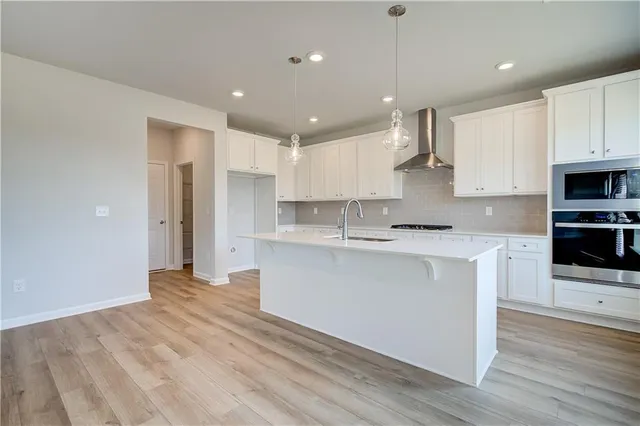 a large white kitchen with kitchen island a sink stainless steel appliances and cabinets