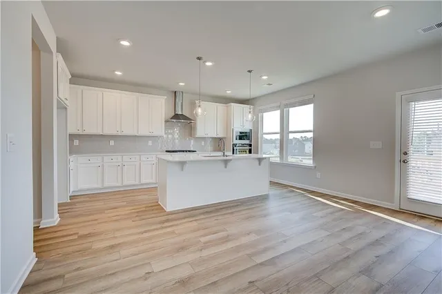 a large kitchen with kitchen island white cabinets wooden floor and a window