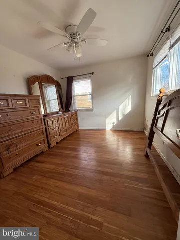a view of an empty room with chandelier fan and wooden floor