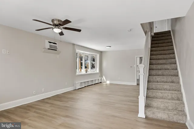 a view of an empty room with wooden floor and ceiling fan