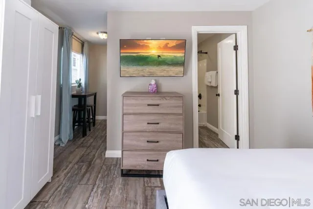 a room with a bed and a flat tv screen on dresser