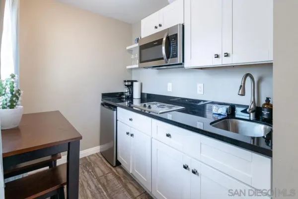 a kitchen with granite countertop white cabinets stainless steel appliances and a sink