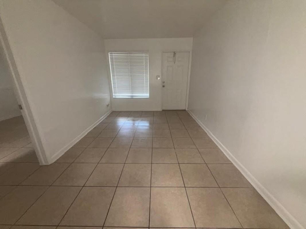 6008 Northwest 10th Street, Unit 3 Pompano Beach, FL 33063 - Photo 2 of 8 an empty room with white walls and tiles
