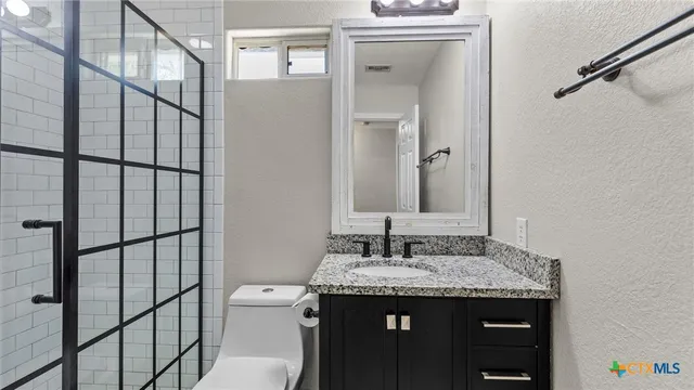 a bathroom with a granite countertop sink toilet and mirror