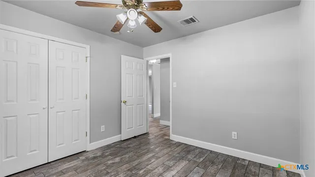 a view of an empty room and chandelier fan