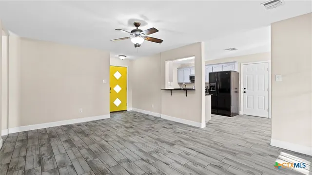 a view of a kitchen with wooden floor a ceiling fan a refrigerator and windows