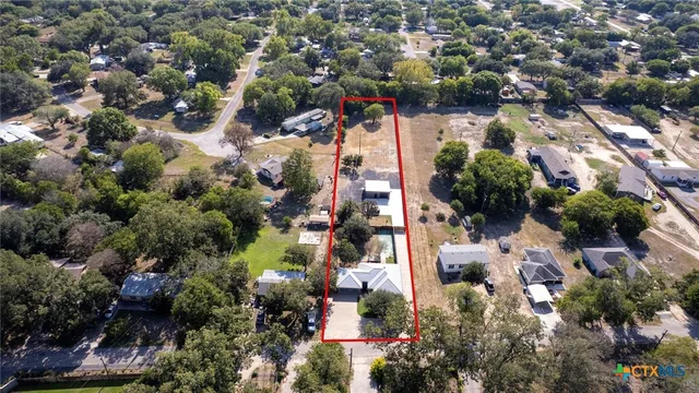 an aerial view of residential houses with outdoor space and trees