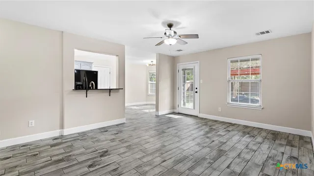 a view of an empty room with window and wooden floor
