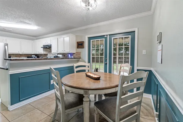 a kitchen with a dining table chairs and refrigerator