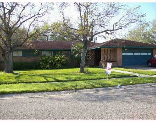 a front view of a house with a yard and a large tree