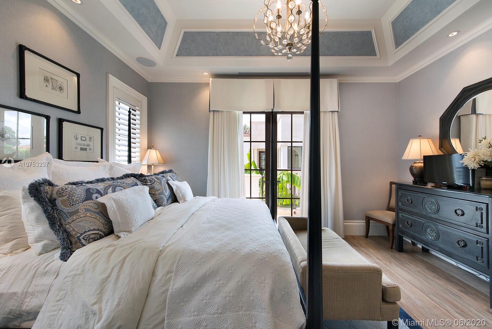 7825 Atlantic Way Miami Beach, FL 33141 - Photo 28 of 38 a bedroom with a bed a chandelier and a flat tv screen on dresser