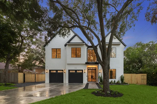 a front view of a house with a yard and a tree