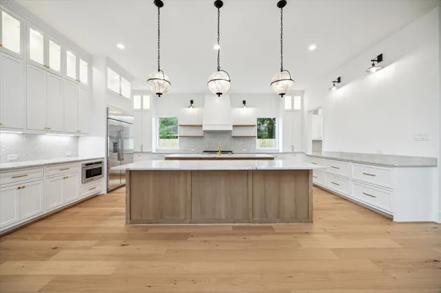 a large kitchen with kitchen island a stove a sink a center island and wooden floor