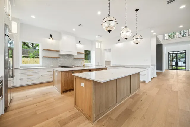 a large kitchen with kitchen island a large island a sink stainless steel appliances and cabinets