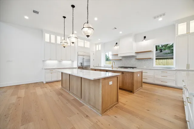 a large kitchen with stainless steel appliances kitchen island granite countertop a sink a counter space and a window