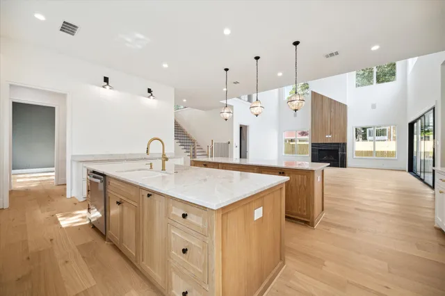 a large white kitchen with a large island oven a sink stainless steel appliances and cabinets