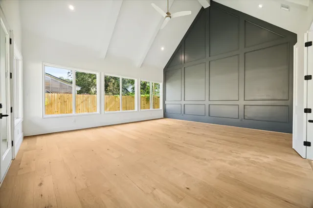a view of an empty room with a window and wooden floor