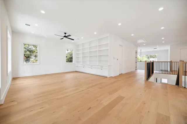 a view of an empty room with a window and kitchen view